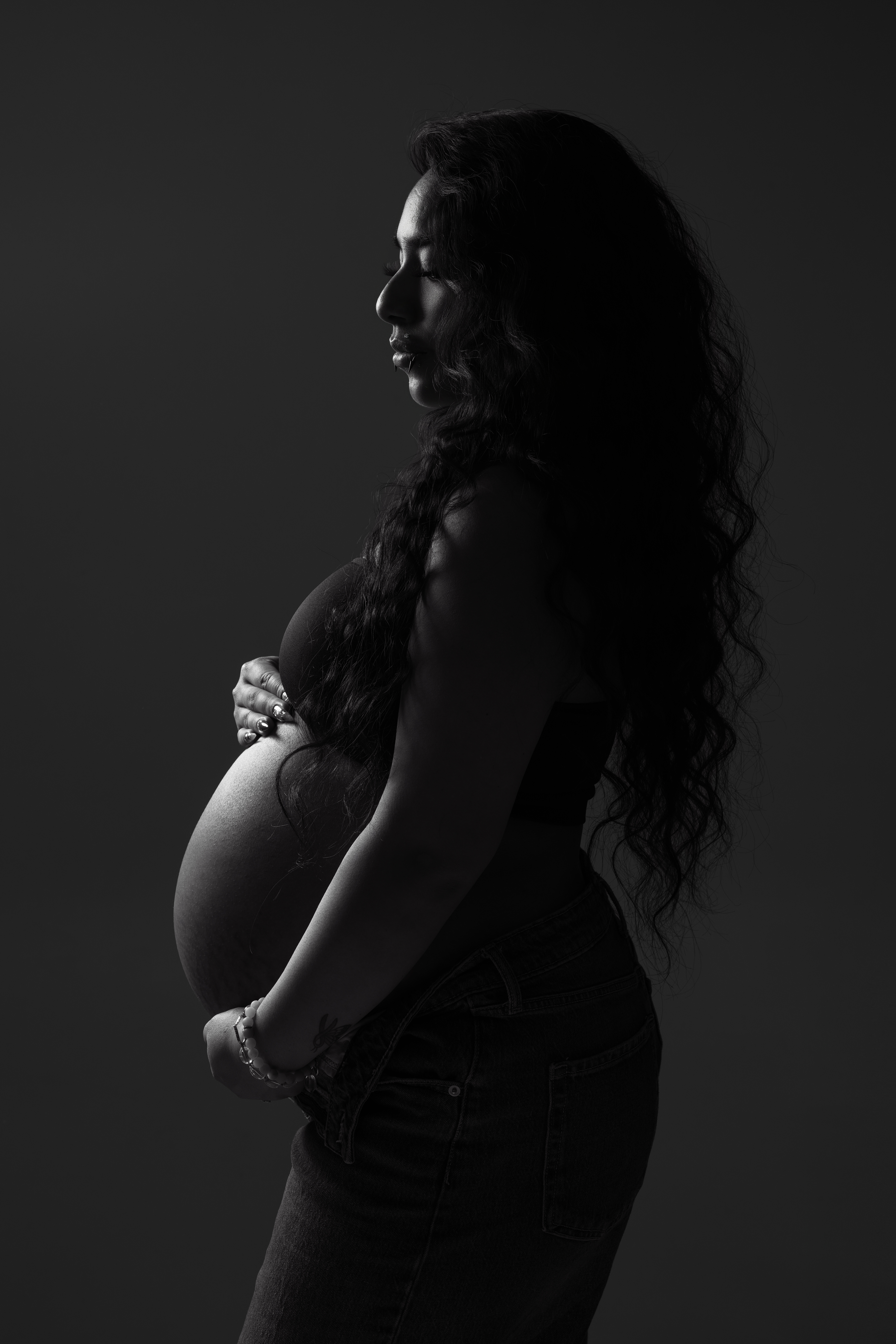Silhouette style maternity portrait of pregnant woman in dramatic studio light
